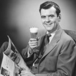 Une homme lit le journal en buvant une bière