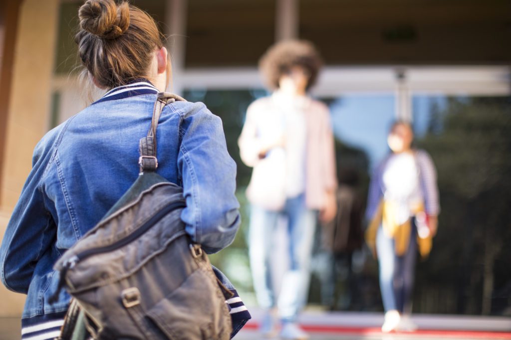professeur et étudiants marchant près d'une école