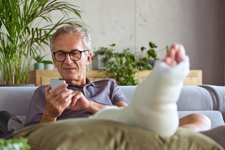 un homme avec une jambe dans le plâtre