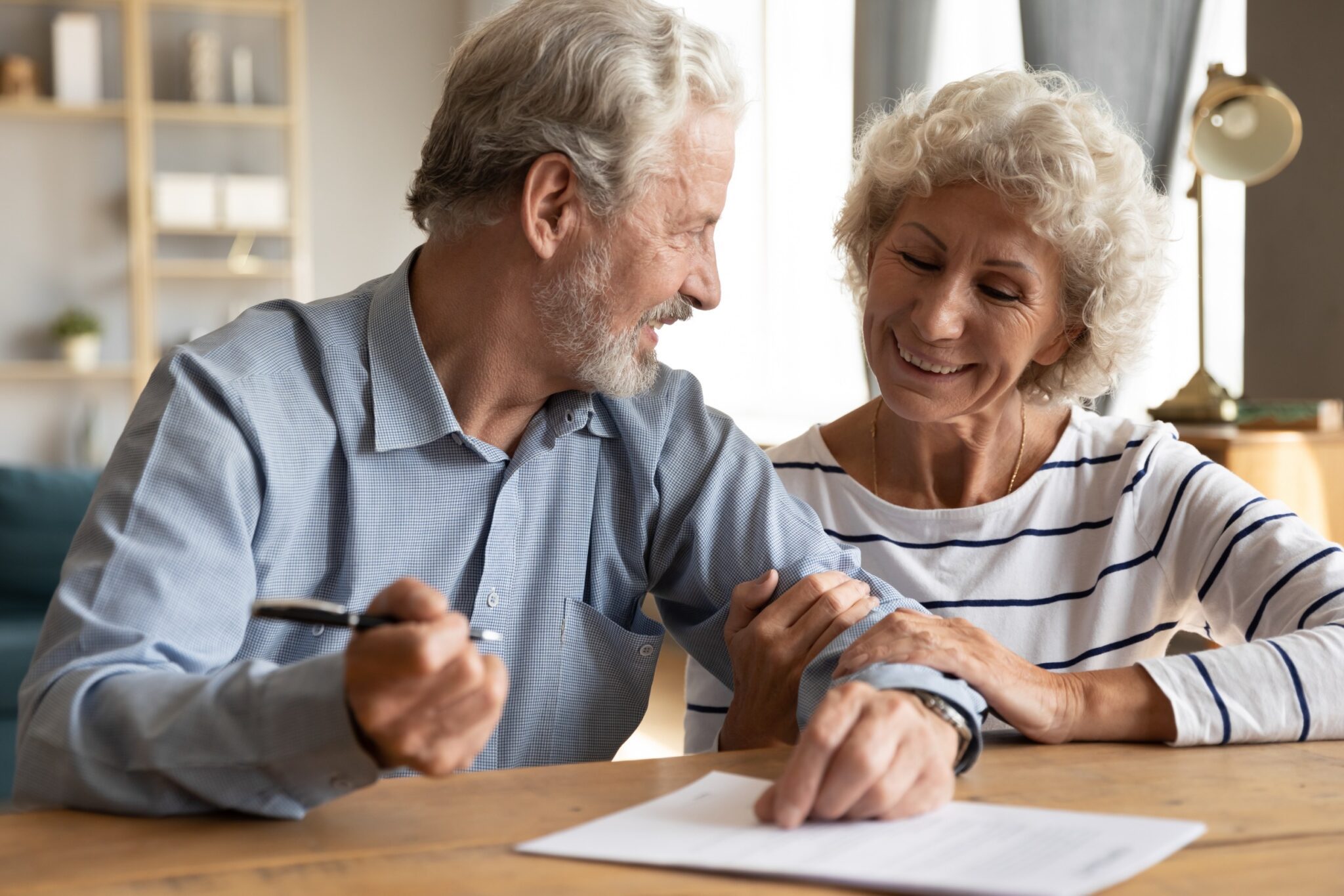 un couple de senior qui signe un document en souriant