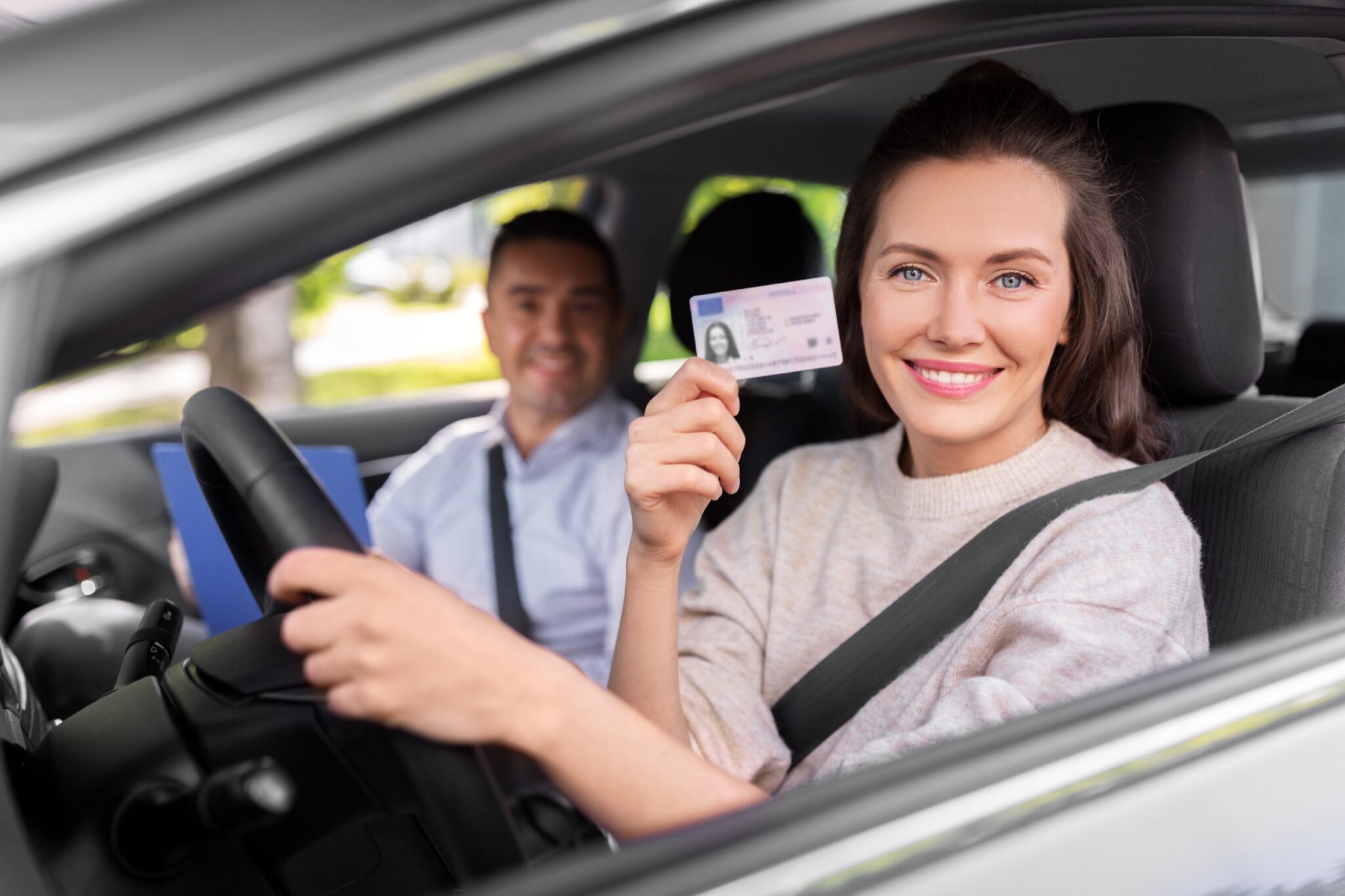 une jeune femme souriante brandissant son permis de conduire fraichement obtenu