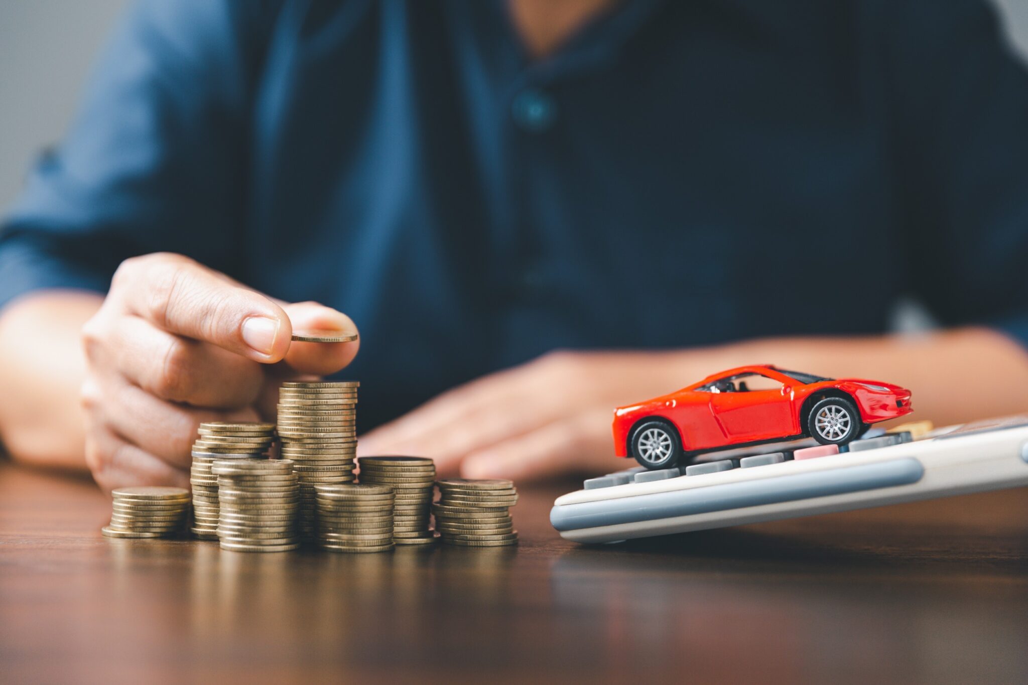 un homme pose des pièces devant une voiture miniature