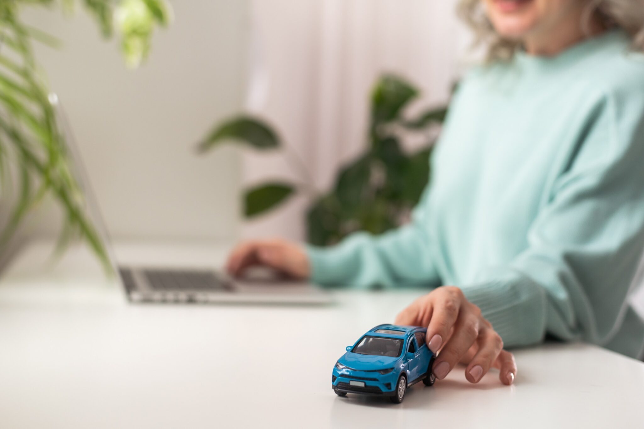 une femme devant un ordinateur avec une voiture miniature