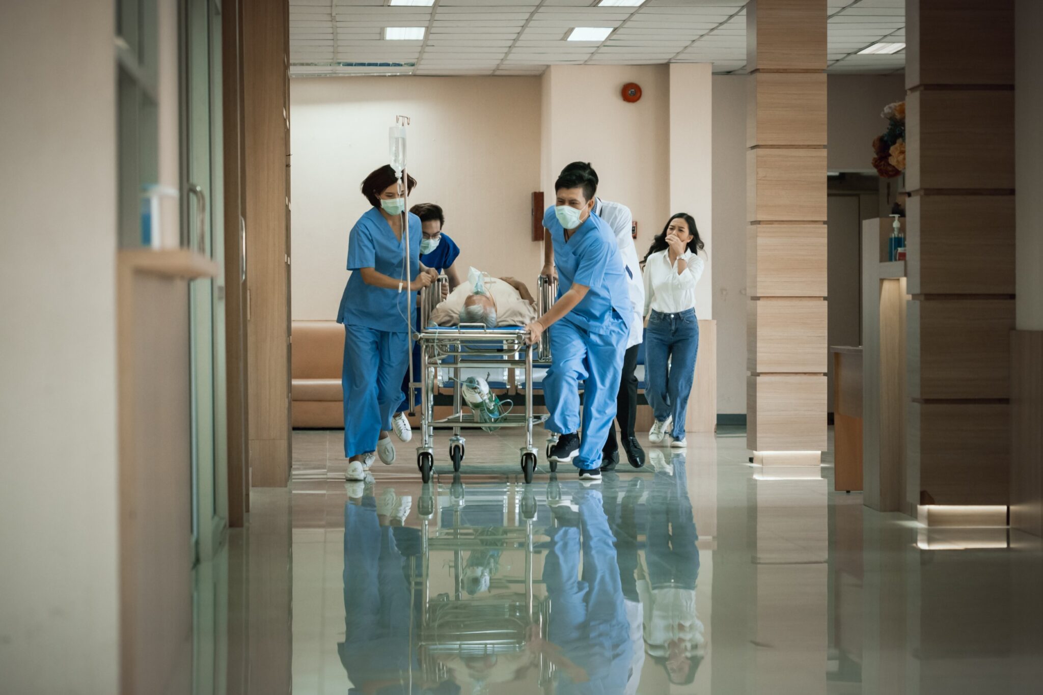 a medical team walks through a hallway with a patient lying on a stretcher 