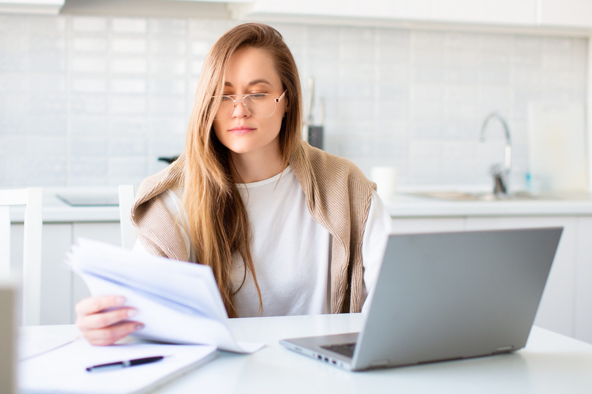 Une femme qui lit des documents devant un ordinateur