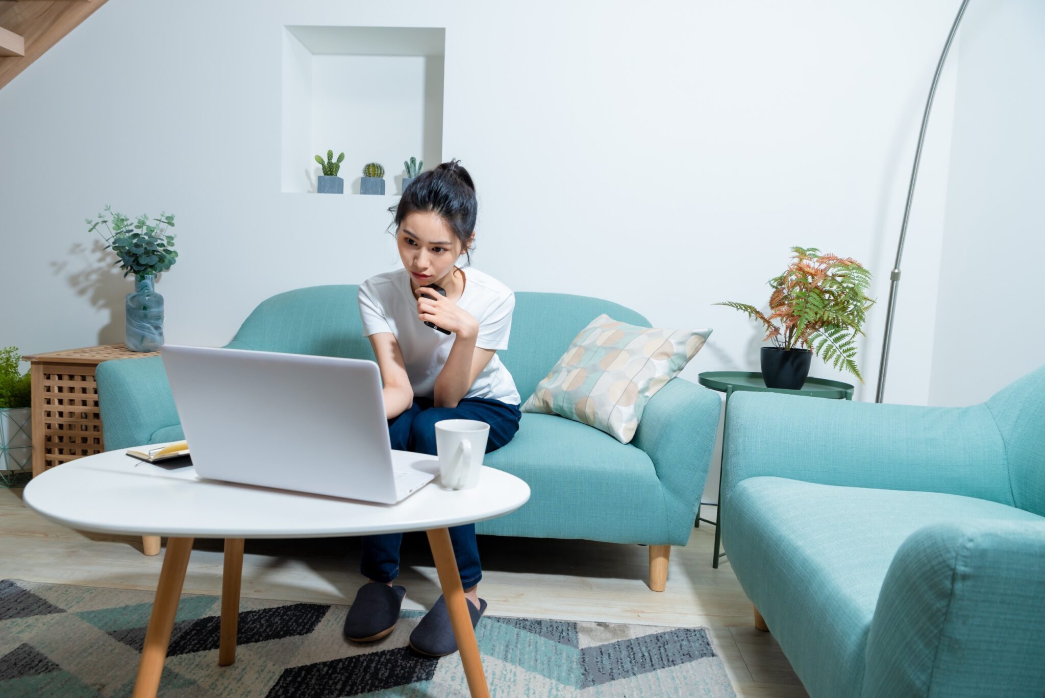une femme est assise sur son canapé et regarde son ordinateur