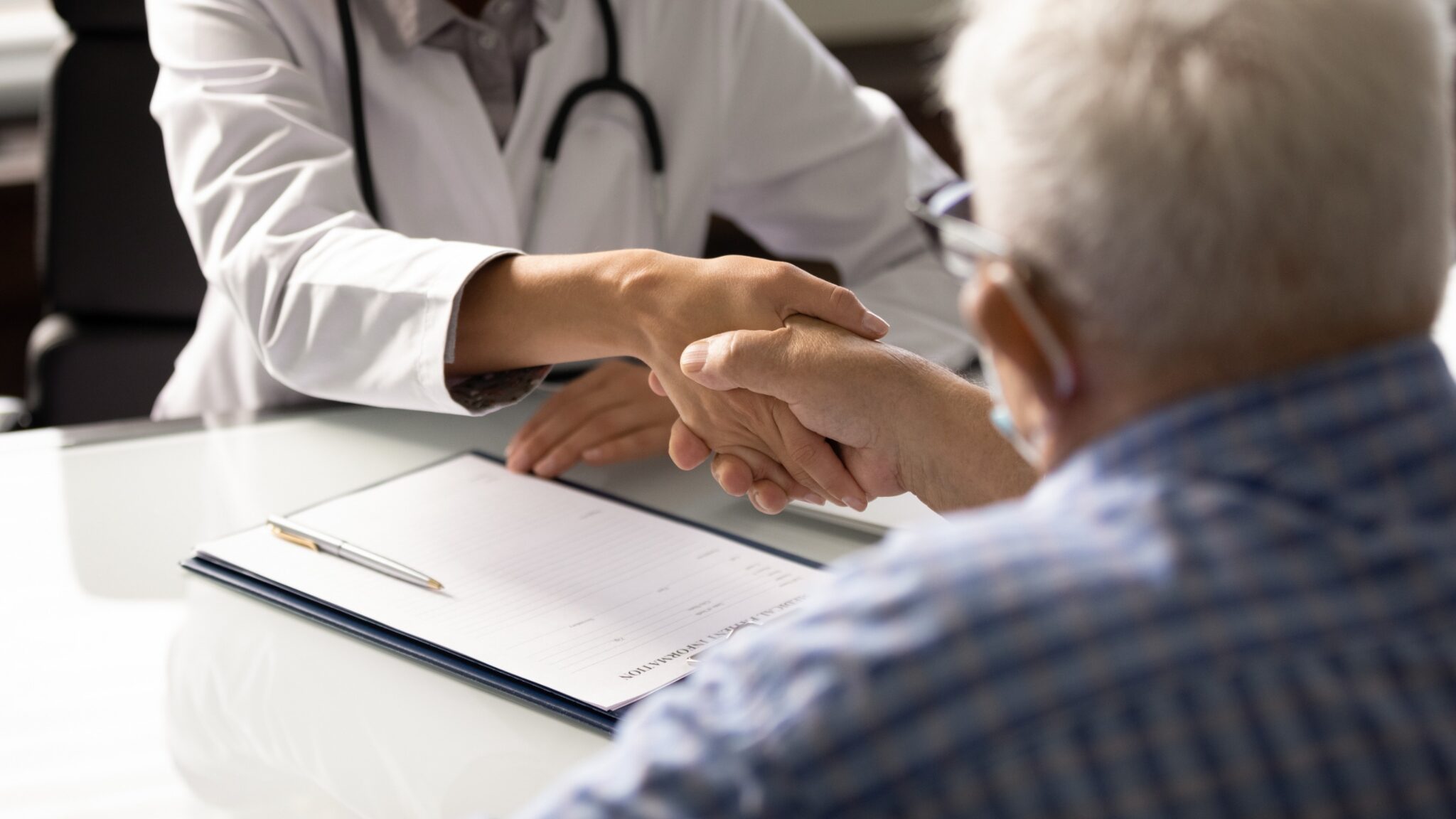 un médecin serre à la main à son patient ayant des cheveux gris