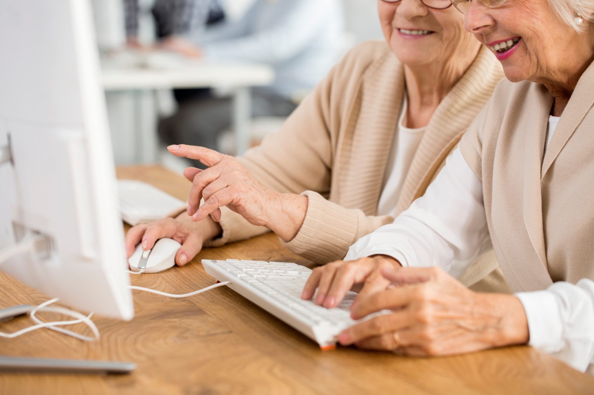deux femmes âgées sourient devant un ordinateur
