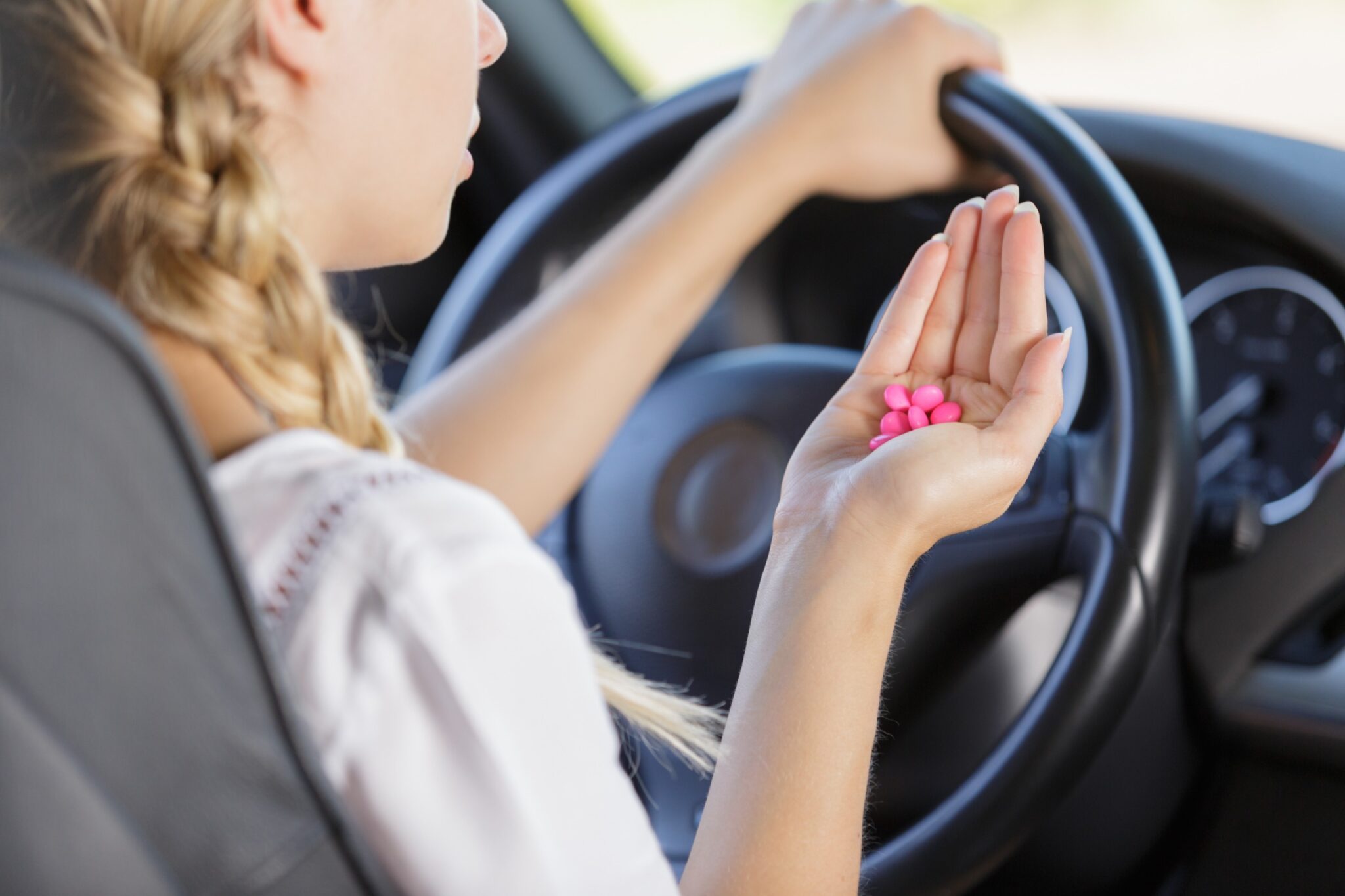 une femme tient des médicaments au volant