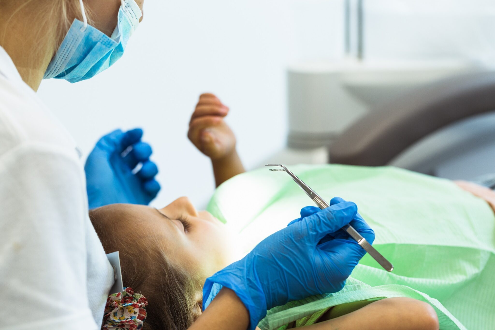 une dentiste est de dos. Elle soigne les dents d'une patiente