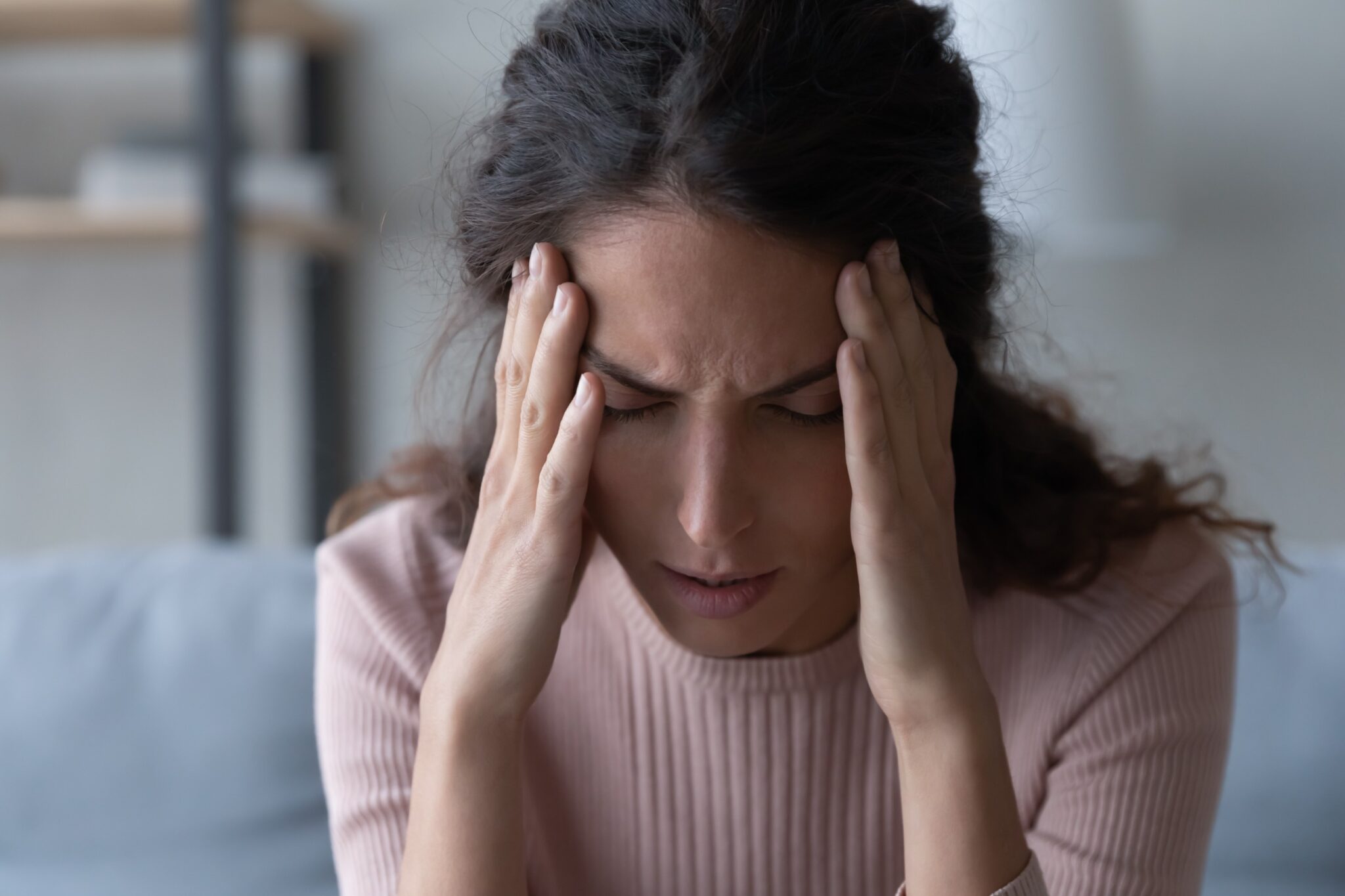 une femme se tient la tête au niveau des tempes