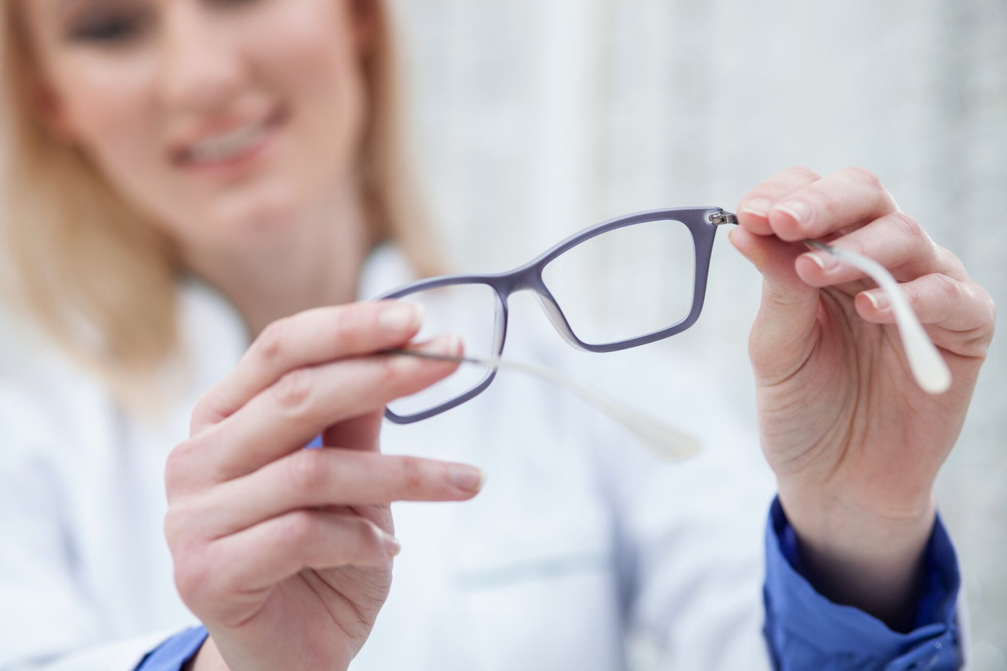 une opticienne tient une paire de lunettes dans ses mains