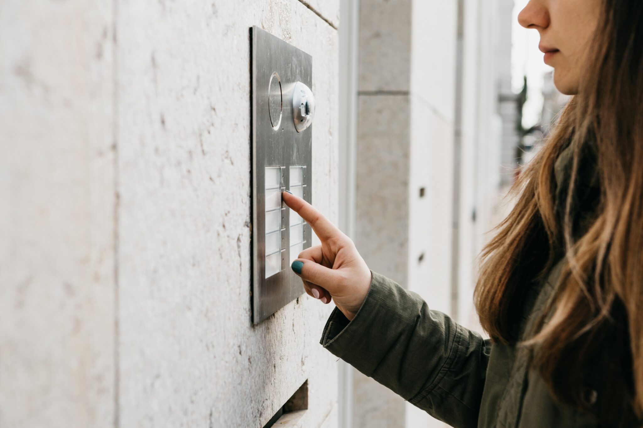 une femme sonne à l'interphone d'un immeuble