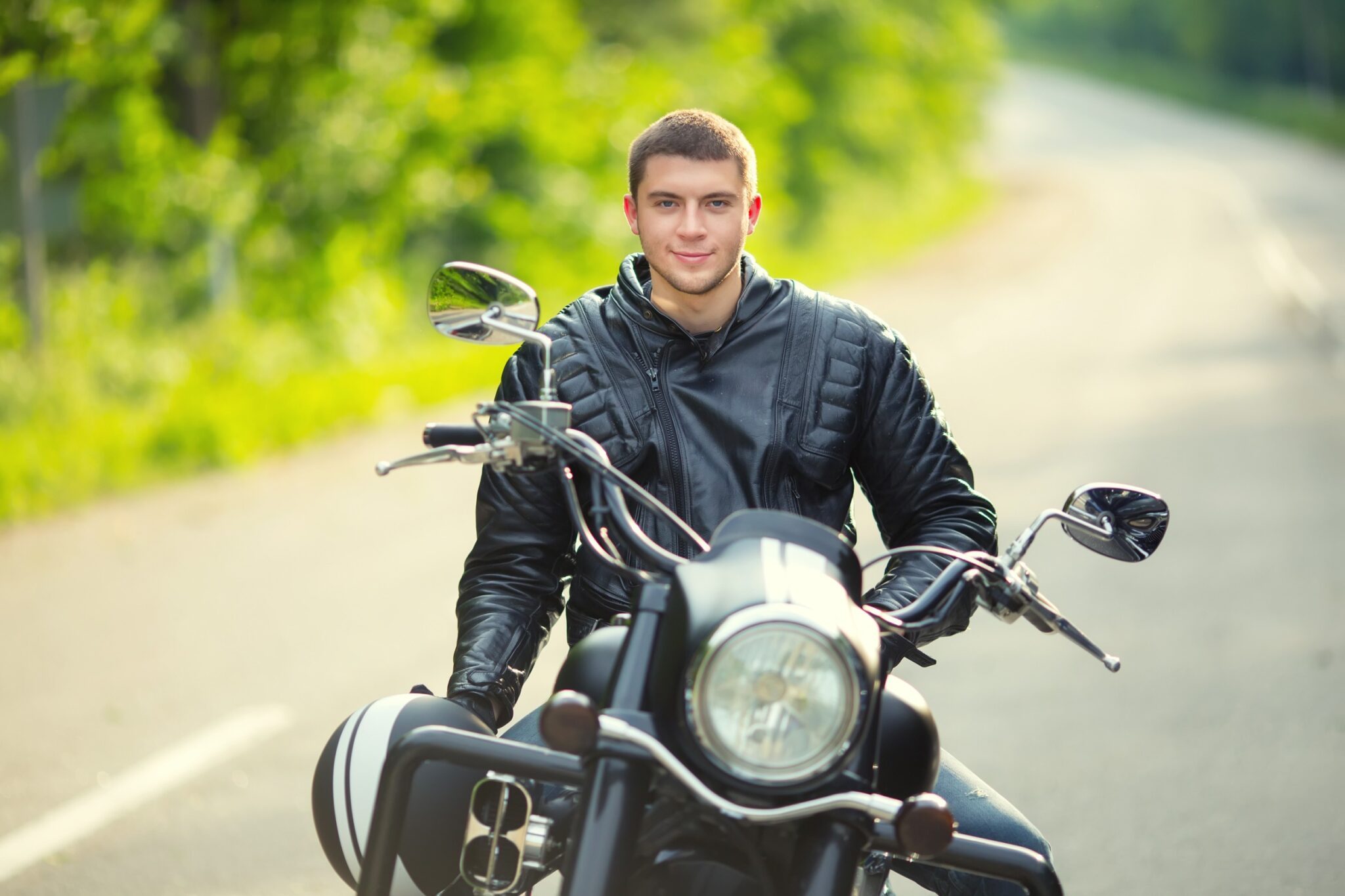 un jeune homme est assis sur sa moto et sourit