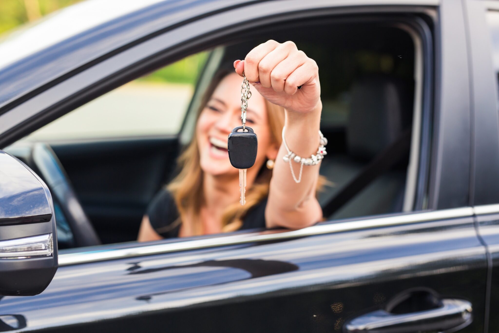 une femme souriante montre ses clés de voiture