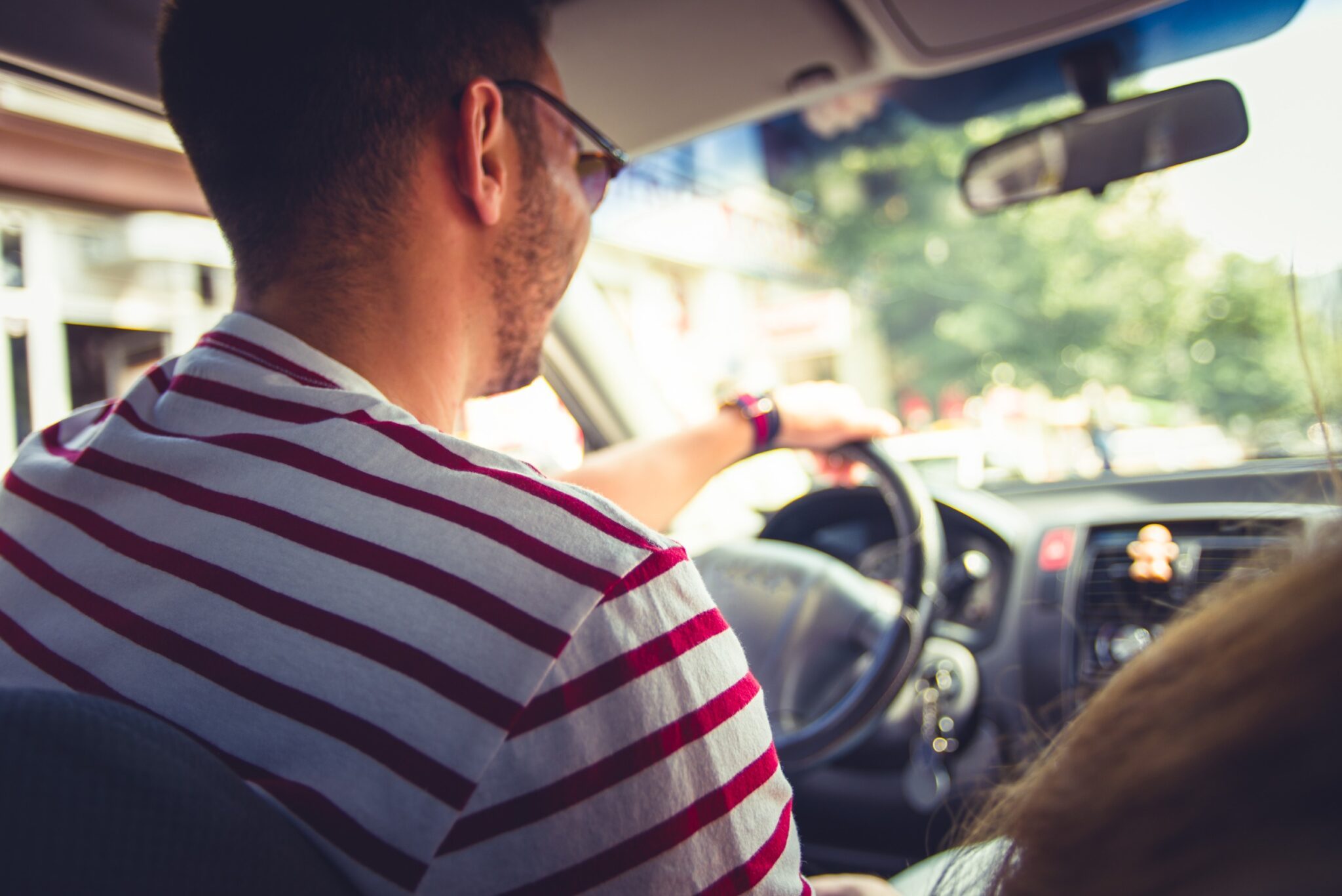 Un conducteur vu de dos au volant de sa voiture