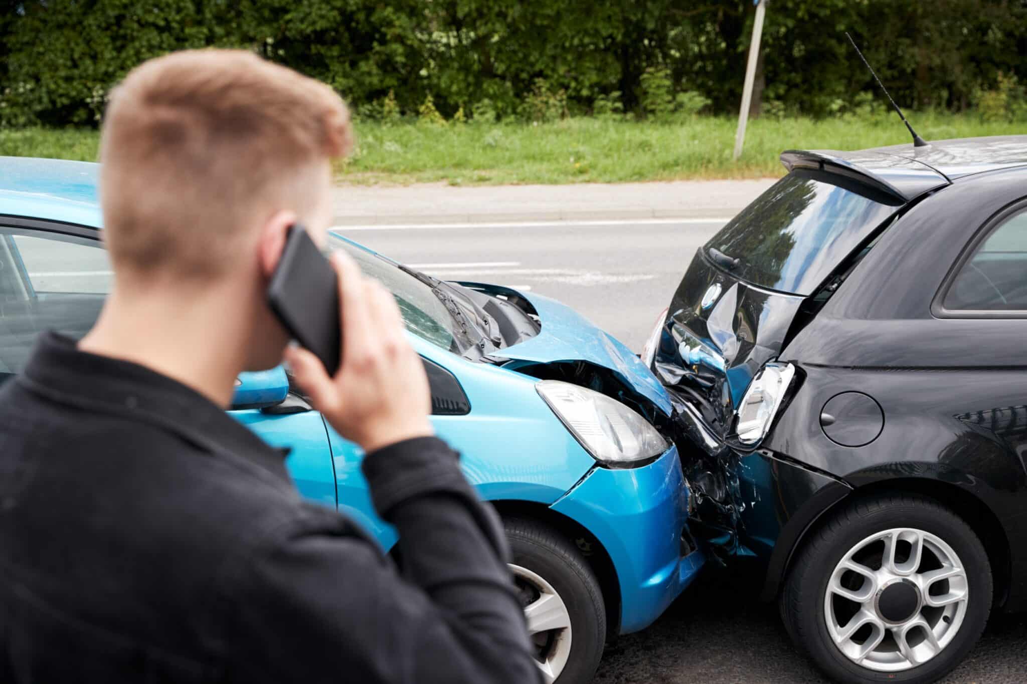 un homme est de dos, au téléphone avec son assurance après avoir subi un accident de la route