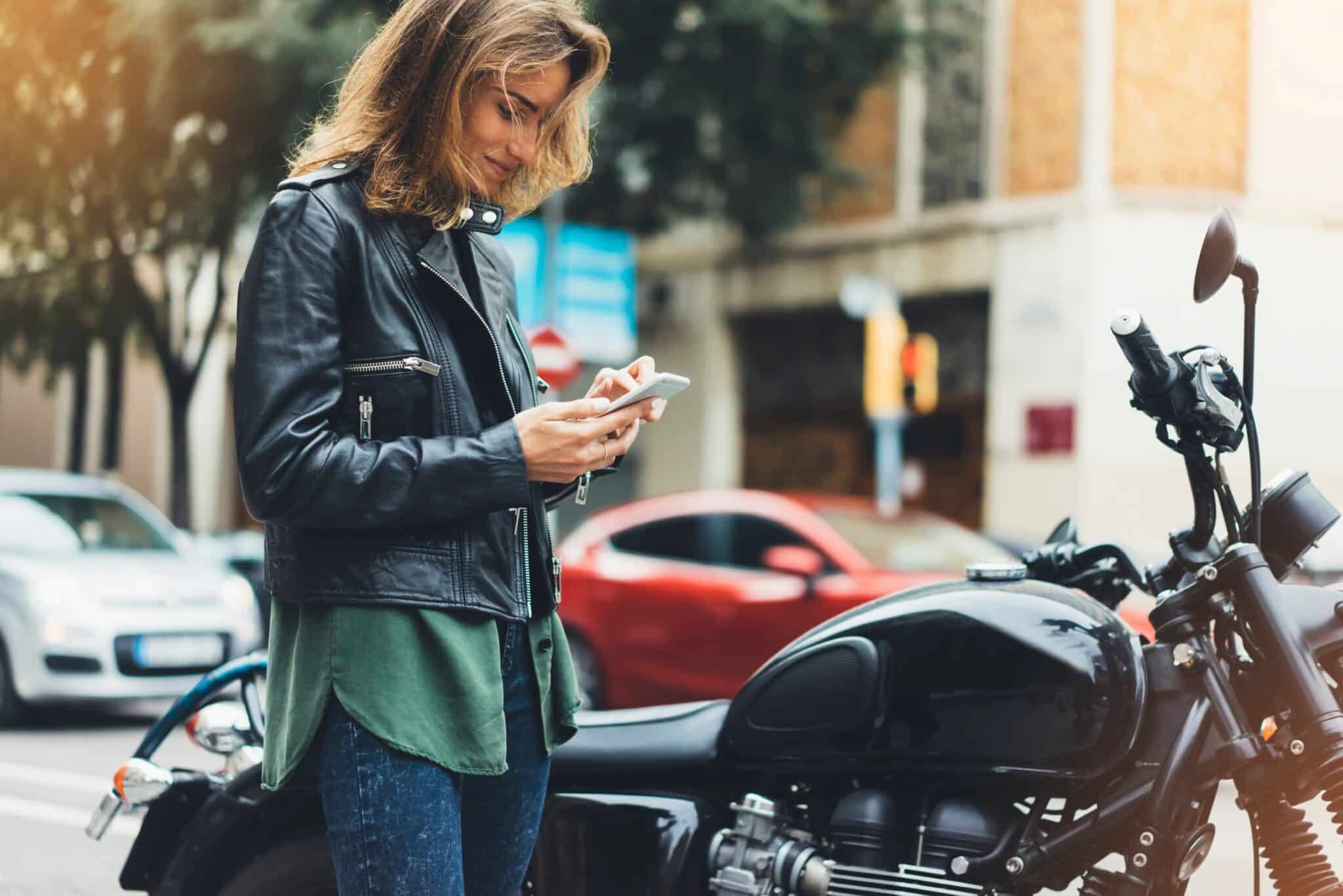Une femme qui regarde son téléphone à côté de sa moto