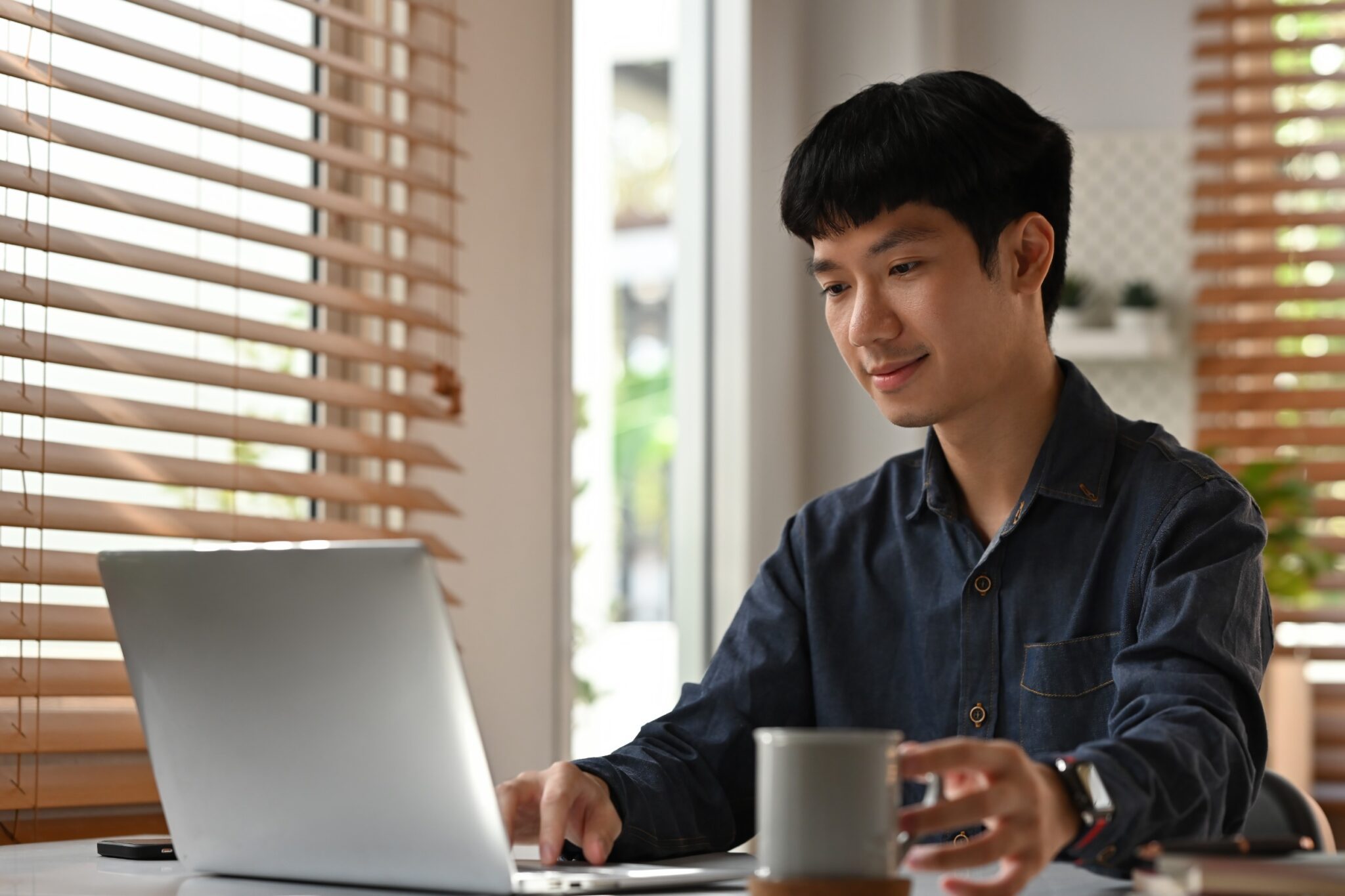 Un homme devant son ordinateur avec une tasse