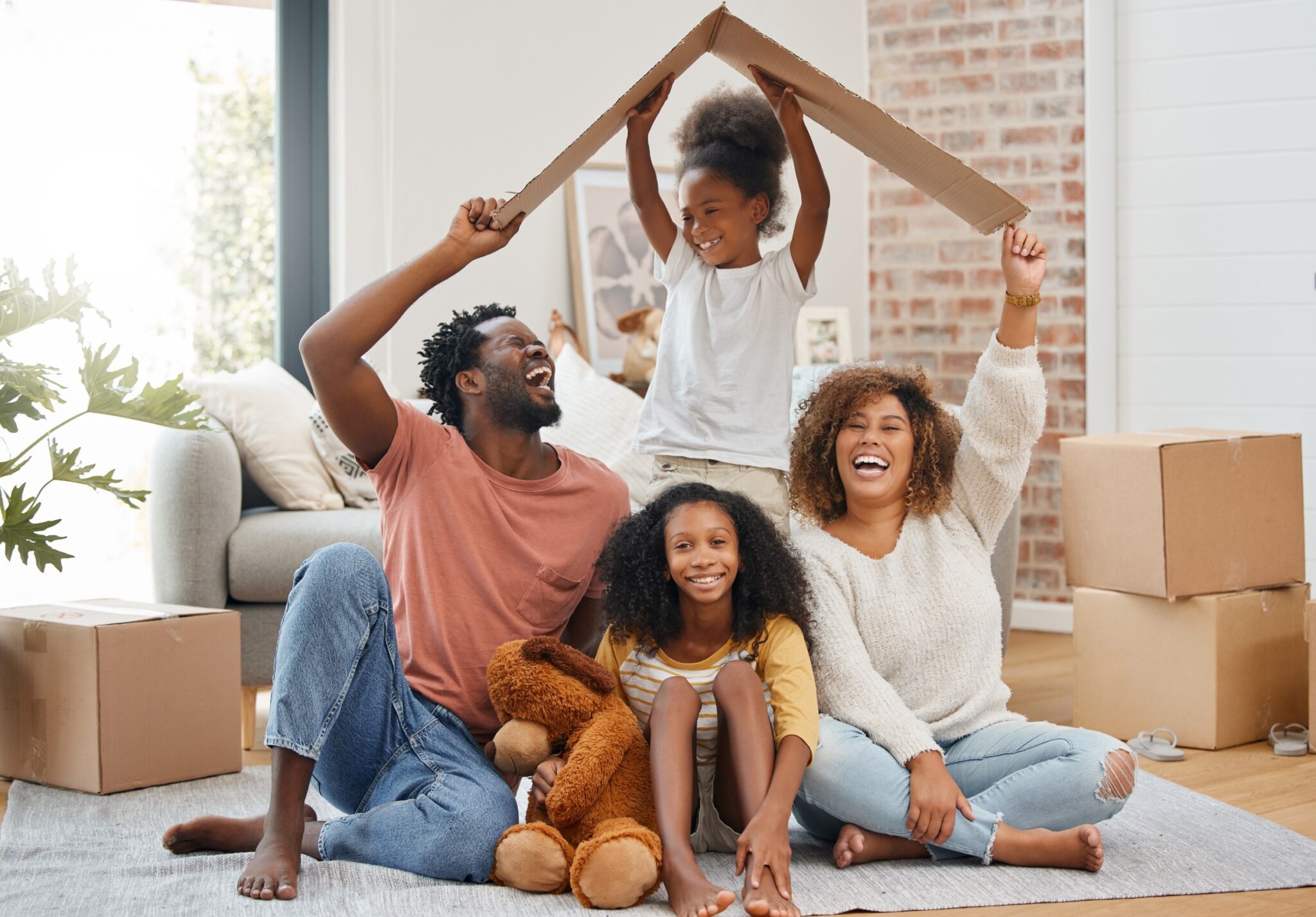 une famille de 5 personnes sourit et forme une maison grâce à un toit en carton