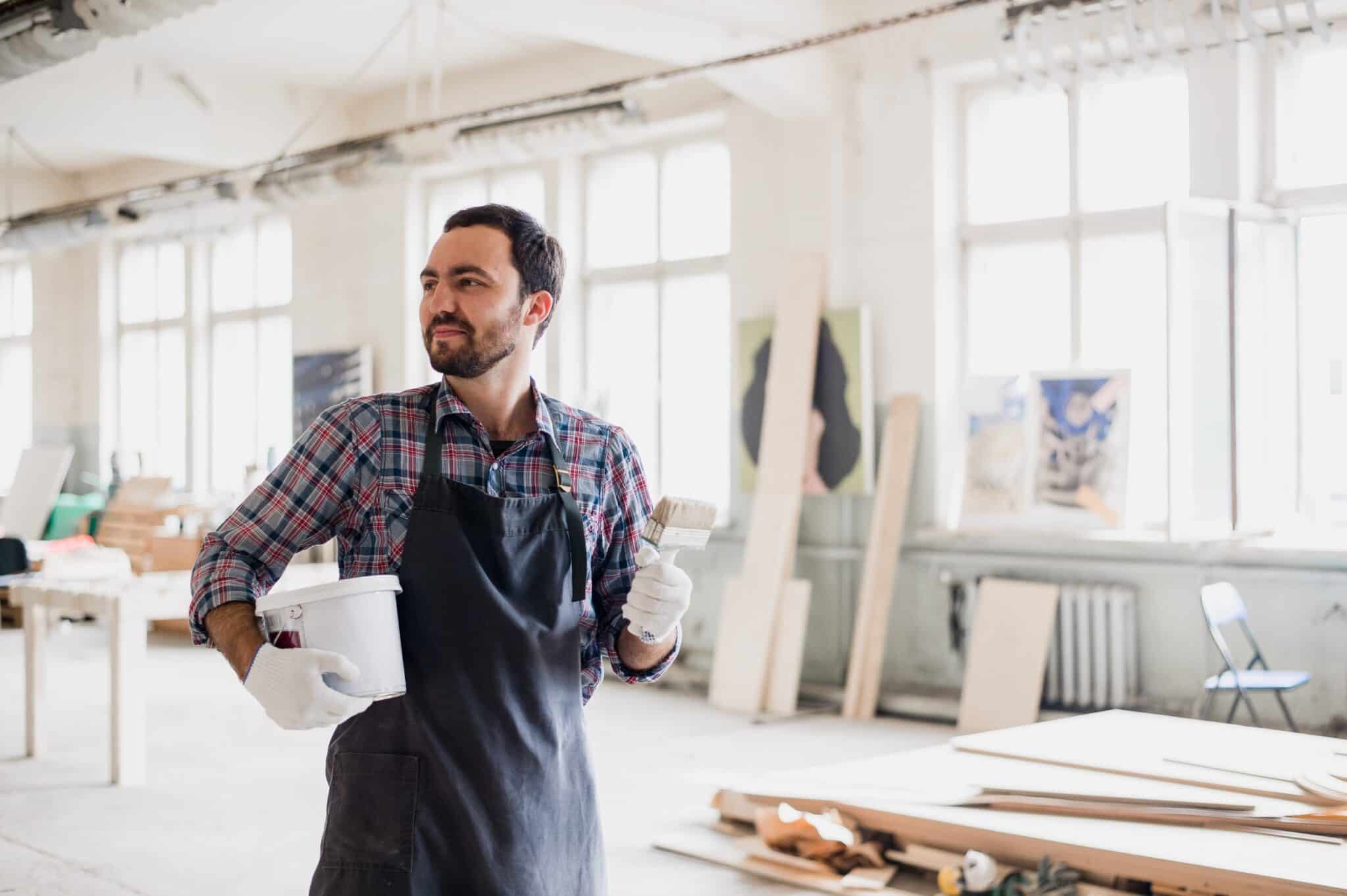 Un homme qui tient un pot de peinture et un pinceau