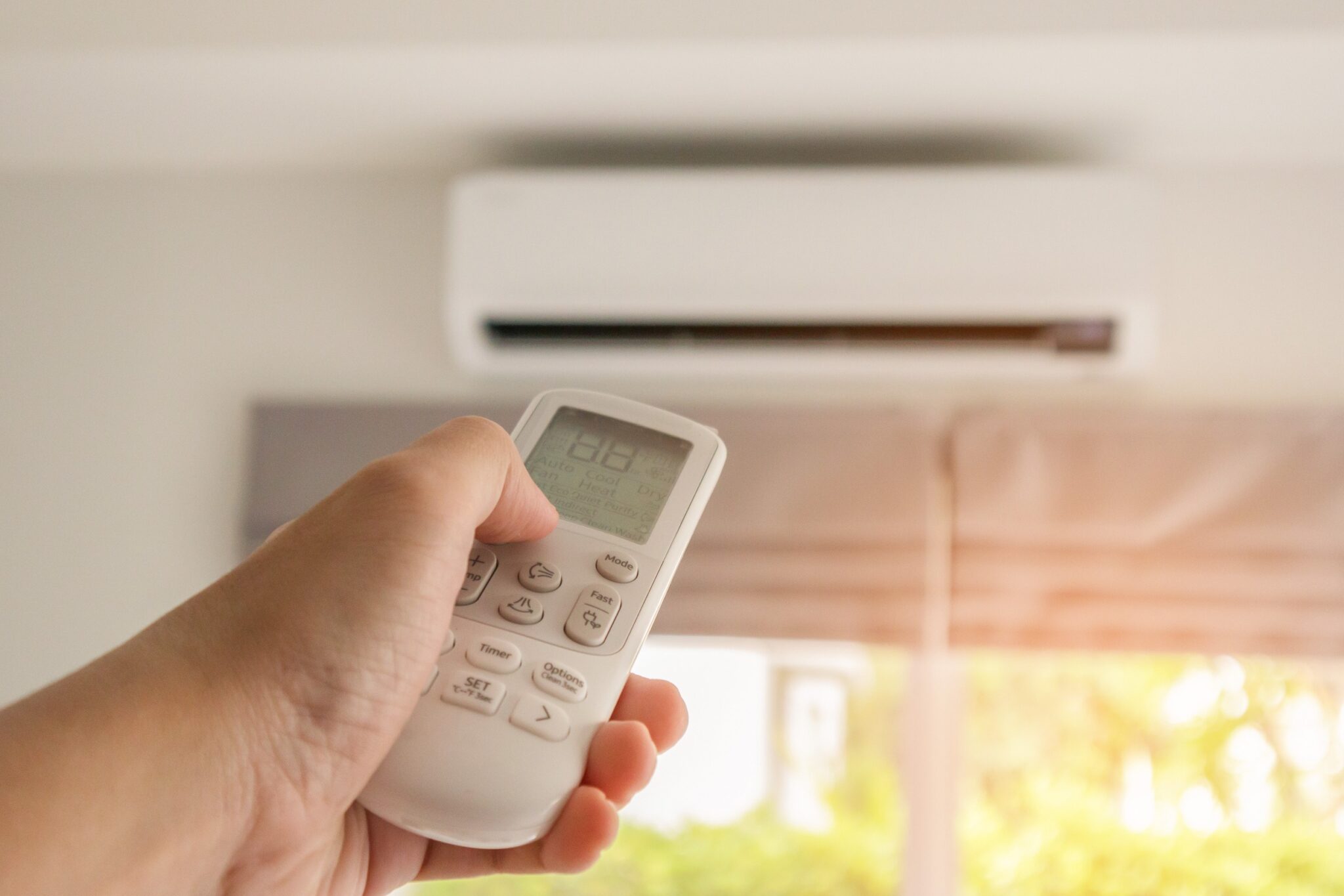 Une main qui tient une télécommande pour régler un climatiseur