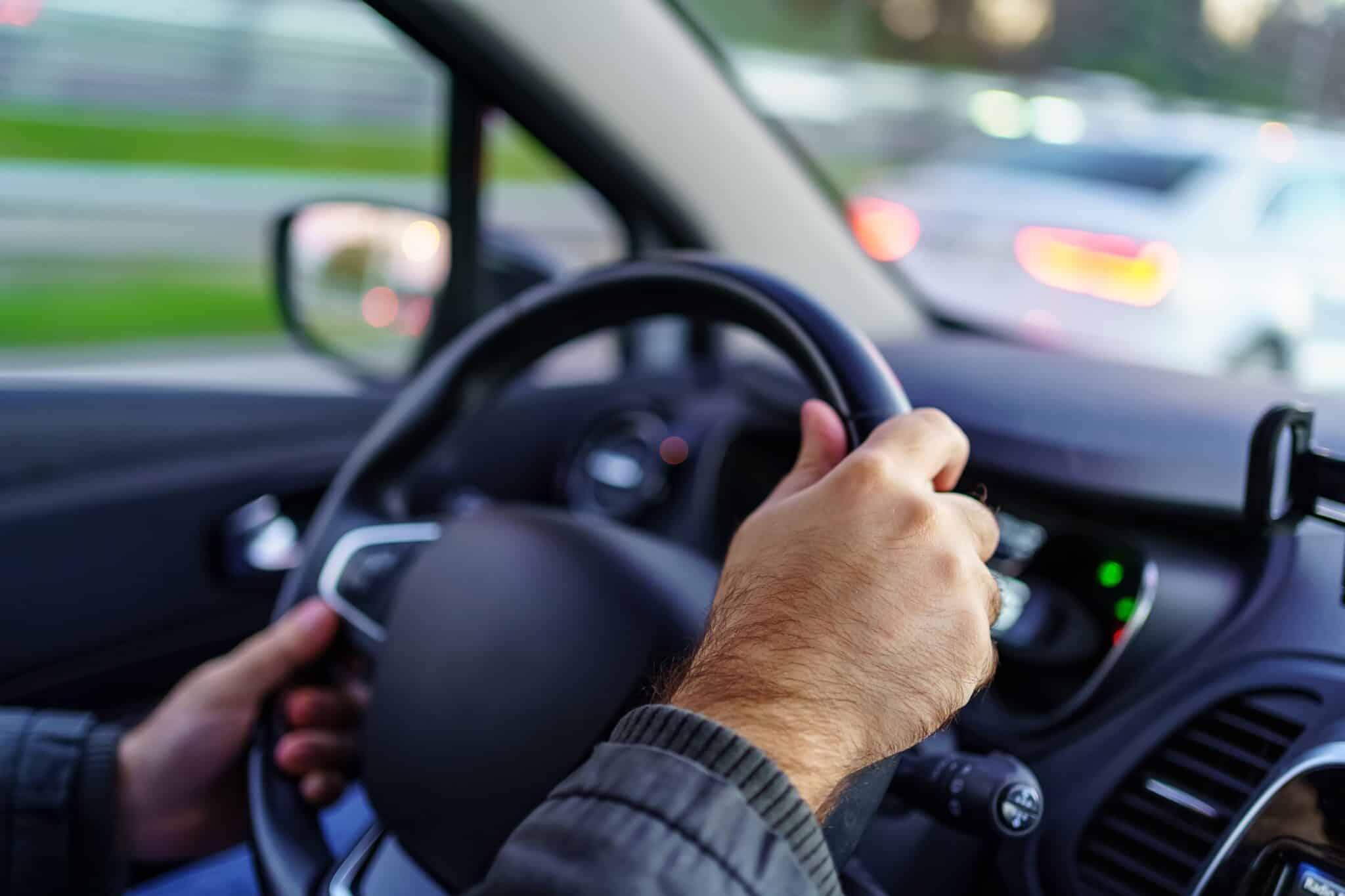 Mains d'un homme sur le volant d'une voiture