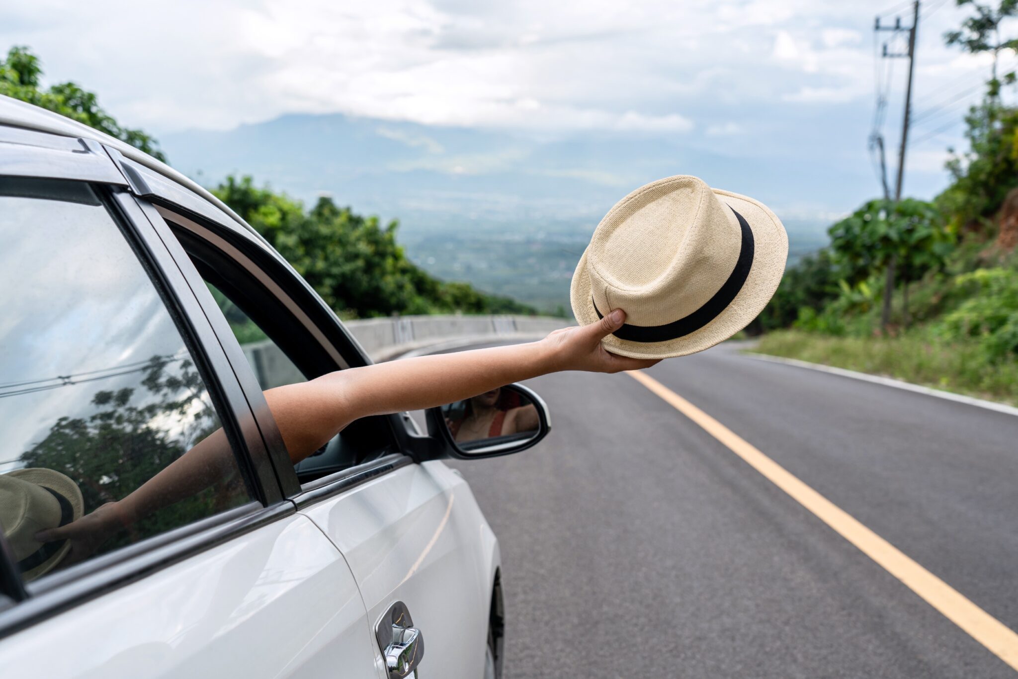 Une personne qui sort un chapeau par la fenêtre d'une voiture