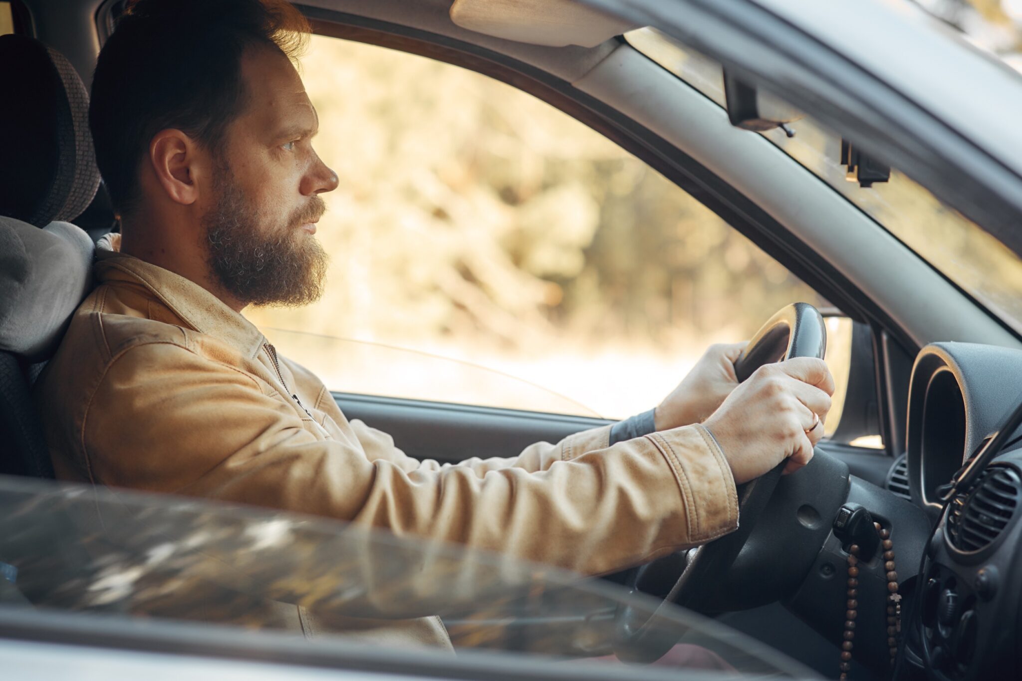 Un homme au volant d'une voiture et qui regarde la route