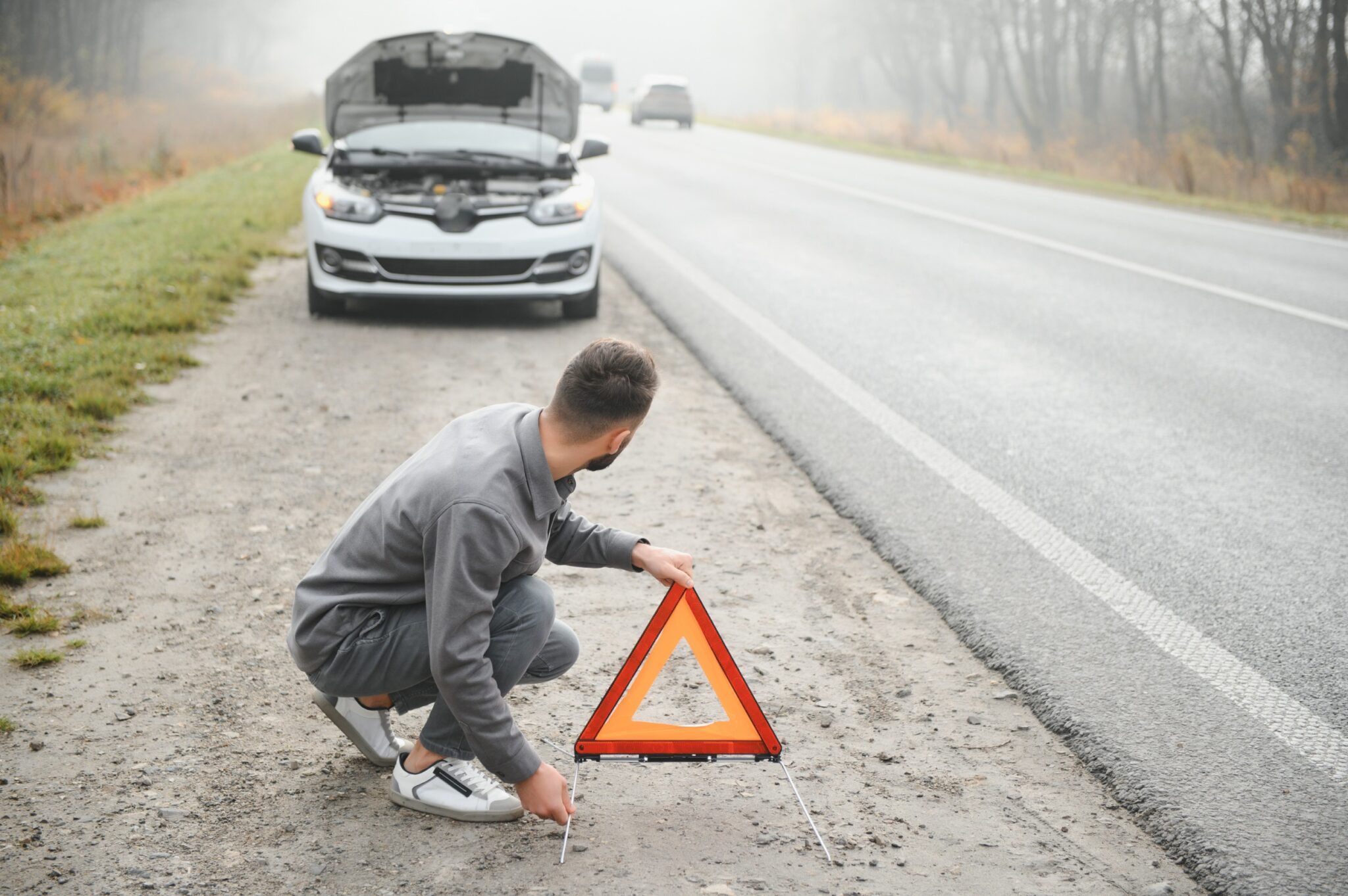 Un homme qui place un triangle suite à une panne de voiture