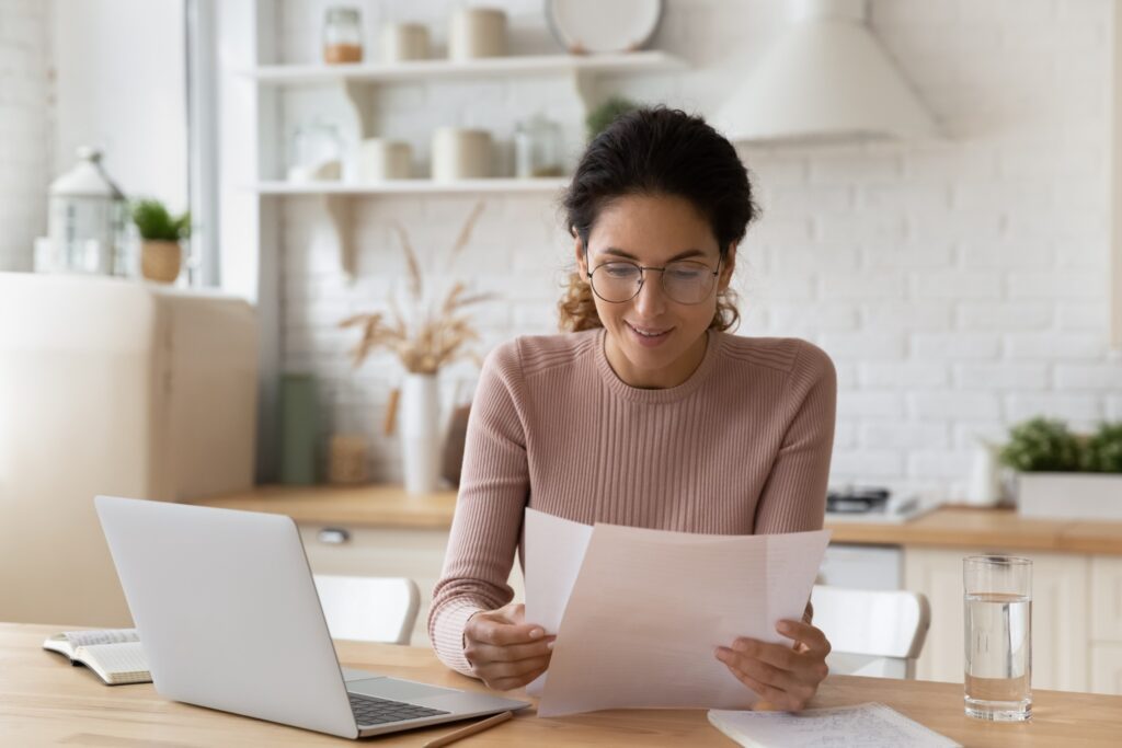 Une femme qui lit des documents devant son ordinateur