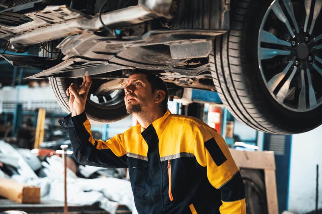 Garagiste vérifiant le dessous d'une voiture