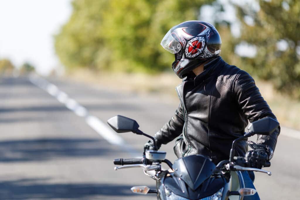 Un homme à moto avec un blouson noir est à l'arrêt