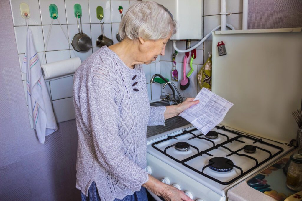 une mamie dans sa cuisie face à sa gazinière et une facture de gaz à la main